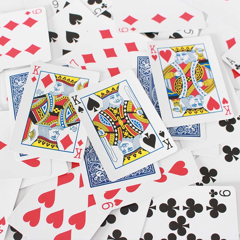 A photo of playing cards all over a white backdrop